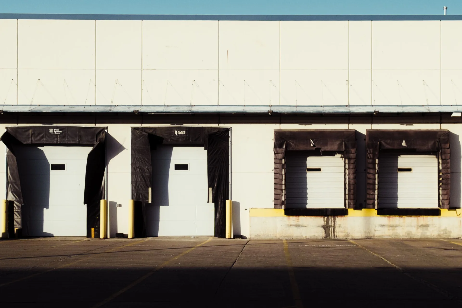 Representative industry photograph of industrial loading-dock doors in daylight.